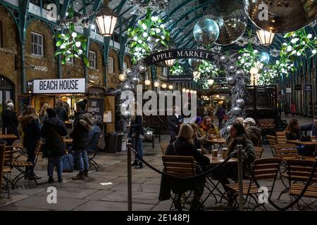 Gli acquirenti di Natale si siedono e portano via un caffè socialmente distanziato nella Covent Garden Piazza durante le misure di Lockdown di Tier2 Coronavirus, Londra UK Foto Stock