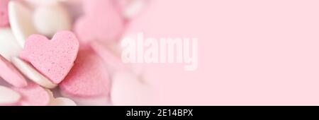Cuori di caramelle di zucchero rosa su sfondo panoramico con copy-space. Banner Web Love, Wedding o San Valentino Foto Stock