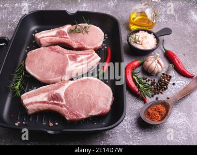 pezzi freschi di carne di maiale cruda, manzo, tritare su un osso, su una padella alla griglia, spezie Foto Stock