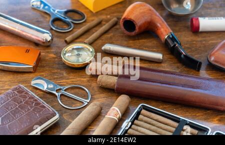 Accessori per fumatori. Sigari, pipe, sigaretti e sigarette, taglierine, accendini, casse su sfondo di un tavolo di legno. Sigari cubani di qualità, l Foto Stock