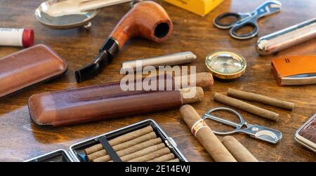 Accessori per fumatori. Sigari, pipe, sigaretti e sigarette, taglierine, accendini, casse su sfondo di un tavolo di legno. Sigari cubani di qualità, l Foto Stock