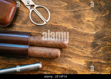 Sigaro e accessori su un tavolo di legno, vista closeup. Sigari cubani di qualità tabacco fumo stile di vita di lusso. Vista dall'alto, spazio di copia del modello Foto Stock