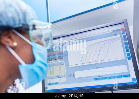 Ricercatore africano presso il monitor del computer durante l'analisi dei dati in Il laboratorio dopo l'esperimento sulla ricerca vaccinale di Covid-19 Foto Stock