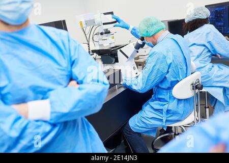 I ricercatori lavorano al microscopio in laboratorio a Covid-19 Pandemic Looking per un vaccino Foto Stock