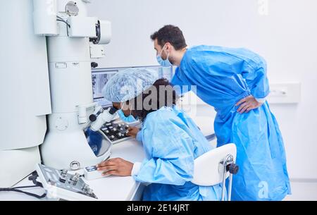 I ricercatori lavorano al microscopio in laboratorio durante l'esame pandemico di Covid-19 per il vaccino Foto Stock