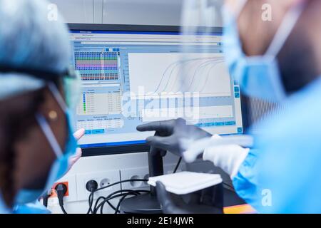 Due ricercatori all'analisi dei dati dell'esperimento in laboratorio sul monitor del computer Foto Stock