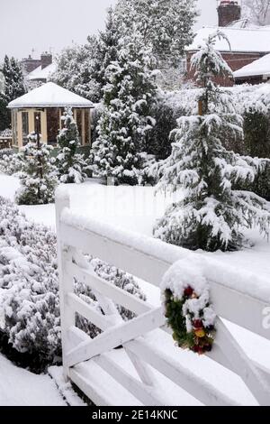 Regno Unito, Inghilterra, Cheshire, Congleton, corona di Natale al cancello esterno, giardino coperto di neve in inverno Foto Stock