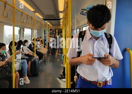 Bangkok, Thailandia - 16 dicembre 2020 : studente asiatico e i passeggeri in treno cielo trasporto pubblico indossare maschera igienica viso controllo pandemia nuovo Foto Stock