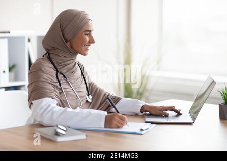 Giovane dottoressa che ha formazione online, seduto nel suo gabinetto Foto Stock