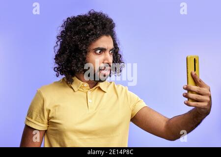 uomo scioccato parlare con la videochiamata telefonica, emotivamente reagisce su qualcosa, vista laterale Foto Stock