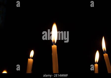 Quattro candele sottili su sfondo scuro. Foto Stock