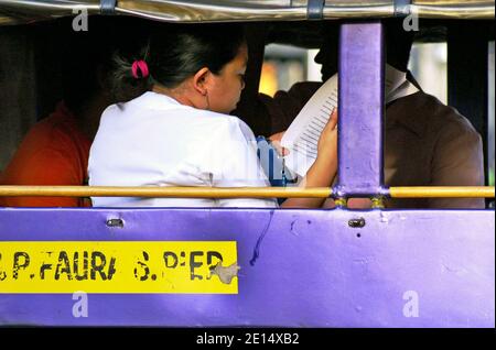 I filippini prendono un Jeepney a Manila, Filippine. Il mezzo di trasporto iconico include jeepney pubblici e privati che si impanano su diversi percorsi scritti sul lato del veicolo. Unica per le Filippine, questa modalità di trasporto ha trovato il suo modello nelle jeep militari in eccesso lasciate dagli Stati Uniti dopo la seconda guerra mondiale Negli ultimi anni i veicoli sono diventati più regolamentati, tra cui un programma di eliminazione graduale dei jeepneys di oltre 15 anni. Foto Stock