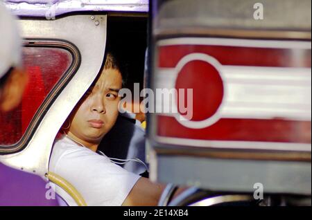 I filippini prendono un Jeepney a Manila, Filippine. Il mezzo di trasporto iconico include jeepney pubblici e privati che si impanano su diversi percorsi scritti sul lato del veicolo. Unica per le Filippine, questa modalità di trasporto ha trovato il suo modello nelle jeep militari in eccesso lasciate dagli Stati Uniti dopo la seconda guerra mondiale Negli ultimi anni i veicoli sono diventati più regolamentati, tra cui un programma di eliminazione graduale dei jeepneys di oltre 15 anni. Foto Stock