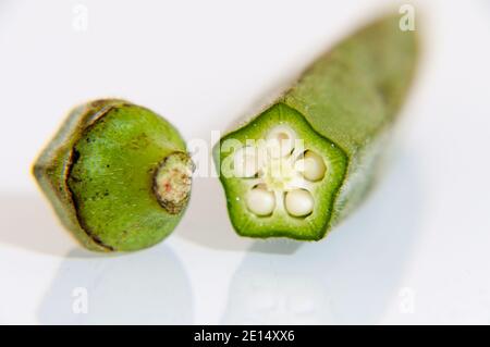 Ochra fresco, Bhindi o Ladies dita tagliate e non cotte su uno sfondo bianco per il taglio Foto Stock