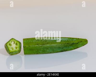 Ochra fresco, Bhindi o Ladies dita tagliate e non cotte su uno sfondo bianco per il taglio Foto Stock