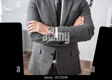 vista dal taglio corto del trader in abbigliamento formale e orologio da polso in piedi con bracci incrociati Foto Stock
