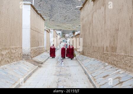 Xiahe, provincia di Gansu, Cina - 28 aprile 2017: Monaci tibetani che camminano lungo un vicolo stretto. Vestita con tradizionale panno rosso. Al monastero di Labrang. Foto Stock