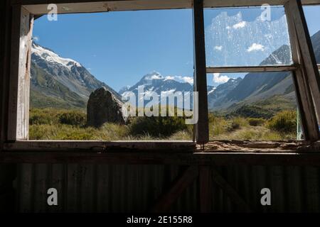 Vista della finestra in vecchio rifugio trampers in montagna, sul Hookers Track, Monte Cook nella regione delle Alpi meridionali della Nuova Zelanda. Foto Stock