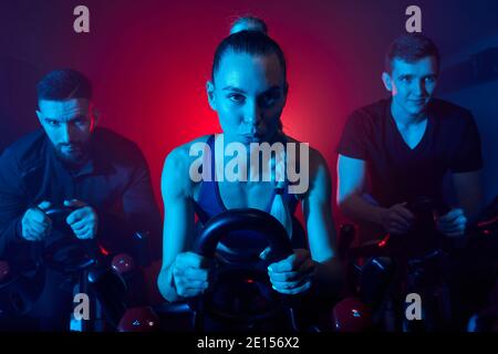 fitness allenamento persone allenarsi su smart cyclette al coperto in palestra nel fitness club, atleta maschile e femminile impegnati nello sport Foto Stock