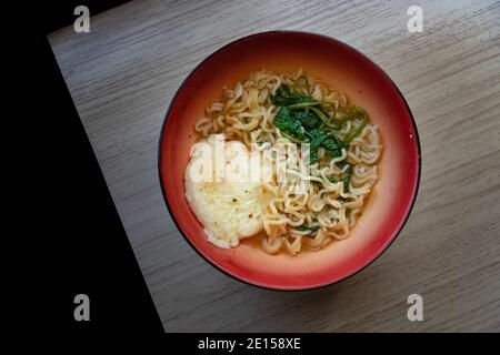 una ciotola di tagliatelle istantanee con uova e verdure vicino la finestra Foto Stock