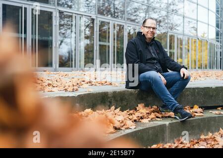 ritratto di un giovane seduto all'aperto in autunno Foto Stock