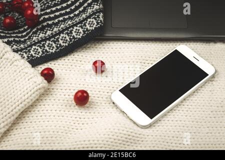 Composizione con sfondo lavorato a maglia, pullover, decorazione e smartphone nero, copy space, foto accogliente Foto Stock