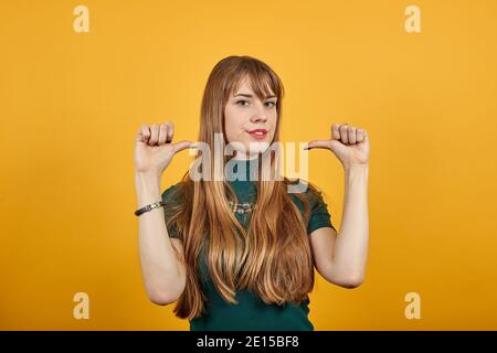 In corrispondenza dello spazio vuoto isolato, puntare il pollice sulla spalla. Punti stupiti con il pollice da parte. Guardate qui. Studio ritratto di foto di sicuro soddisfatto, raccomandando allegro bello umano offrendo nuova soluzione Foto Stock