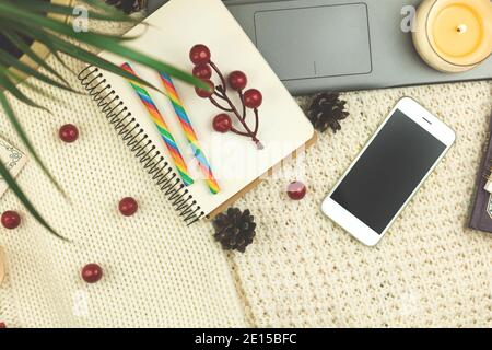 Composizione piatta, sfondo invernale accogliente con cibo, caramelle, smartphone e decorazioni, luogo di lavoro o spazio di lavoro per le foto di vacanza Foto Stock