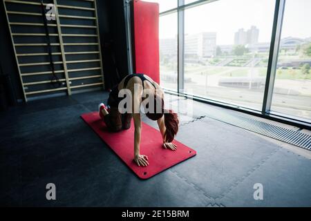 Colpo di donna di idoneità sul tappeto di esercitazione. Atleta femminile sdraiata sulla schiena facendo ginnastica Foto Stock