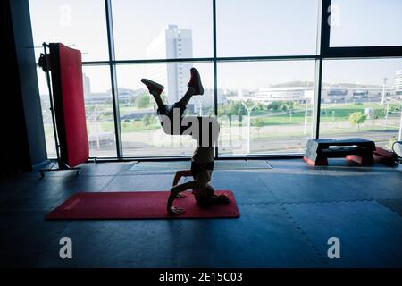 Colpo di donna di idoneità sul tappeto di esercitazione. Atleta femminile sdraiata sulla schiena facendo ginnastica Foto Stock