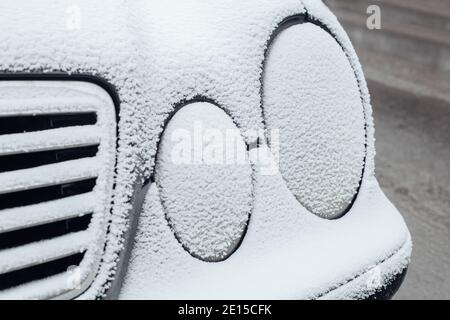 Fari per auto congelati e ricoperti di ghiaccio - condensa e presenza di ghiaccio gelo sulla superficie della vettura Foto Stock