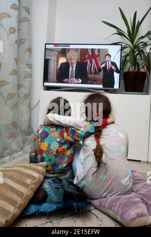 Chichester, West Sussex, Regno Unito. Firenze, 5, (a sinistra) e sua sorella Isabelle, 8, (a destra) guardando il primo ministro britannico Boris Johnson che ha pronunciato il suo discorso alle 20:00 lunedì 4 gennaio 2021 mettendo il Regno Unito in esso è 3 ° Lockdown e chiudere le scuole. Credit: Sam Stephenson/Alamy Live News Foto Stock