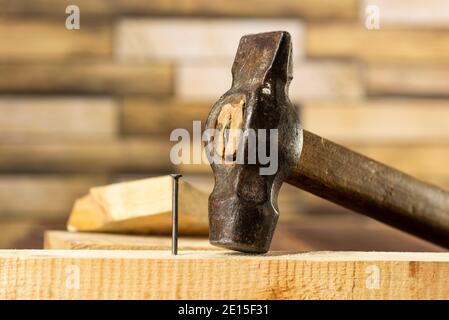 Martellare un chiodo in una tavola di legno, lavoro, carpenteria, primo piano martellare un chiodo Foto Stock