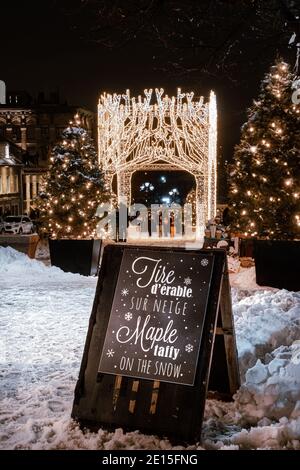 Montreal, Quebec, Canada - 3 gennaio 2021 UN segno che offre Taffy acero sulla neve nel posto Jacques-Cartier nella Vecchia Montreal con luci di Natale Foto Stock