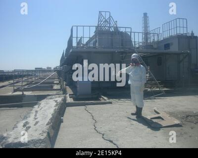 Un operaio che indossa una tuta protettiva punta in una fossa di cemento fessurato vicino al suo reattore n. 2 della centrale nucleare Fukushima Daiichi di Tokyo Electric Power Co. (TEPCO) nella prefettura di Fukushima, Giappone, 2 aprile 2011. L'operatore della centrale nucleare giapponese colpita ha detto il sabato che aveva trovato l'acqua radioattiva che fuoriesce in mare da una fossa di calcestruzzo fessurata nel suo reattore n. 2 a Fukushima. TEPCO ha detto che la radiazione nella buca misurava 1,000 millidi all'ora. Foto tramite ABACAPRESS.COM Foto Stock