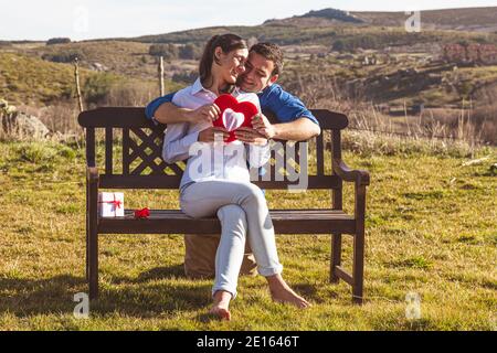 Giovane coppia abbracciando, baciandosi e godendosi passare il tempo insieme mentre festeggia San Valentino nella campagna. Amore san valentin e R. Foto Stock
