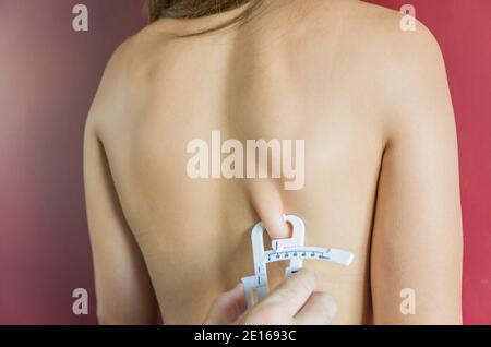 Misurare il grasso corporeo di una donna utilizzando un adipometro. Foto Stock