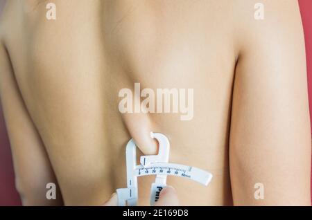 Misurare il grasso corporeo di una donna utilizzando un adipometro. Foto Stock