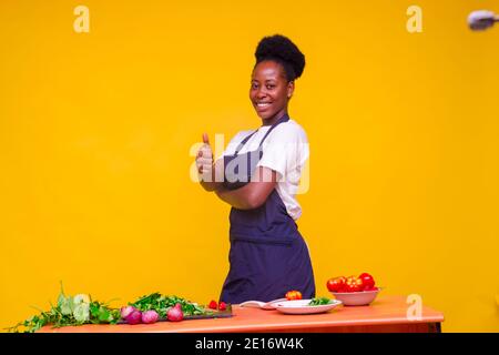 una giovane donna africana si sente eccitata in cucina mentre ha fatto i pollici in su Foto Stock