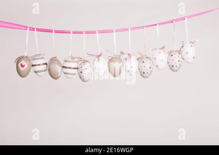 uova di pasqua appese in nastro rosa Foto Stock