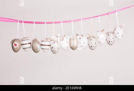 uova di pasqua appese in nastro rosa Foto Stock