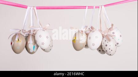 uova di pasqua appese in nastro rosa Foto Stock