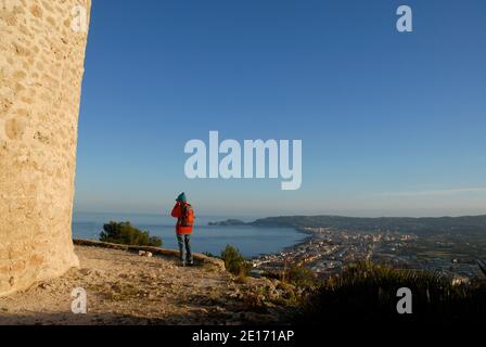 Donna che scatta una foto, in piedi accanto ad un mulino a vento sulla punta che guarda Javea e la Costa Blanca, Provincia di Alicante, Spagna Foto Stock