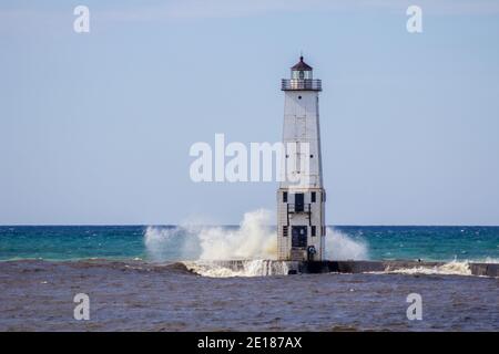 Onde sul faro. Le onde si infrangono sul vecchio faro di Frankfort sulla costa del lago Michigan. Foto Stock