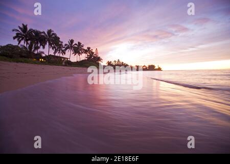 Sunset on Waialua Beach, with calm waves in foreground Stock Photo