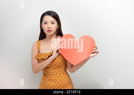 ritratto di donna asiatica felice che tiene il simbolo del cuore rosso Foto Stock