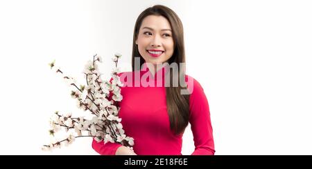 Felice sorridente giovane donna asiatica che tiene rami di pesca albero con fiori in fiore Foto Stock