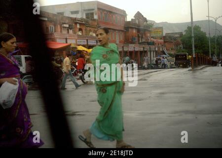 Donne che attraversano una strada ad un incrocio dopo una pioggia pesante a Jaipur, Rajasthan, India. Foto Stock