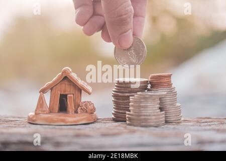 Mano selezionare monete impilare modello casa su tavola di legno Foto Stock