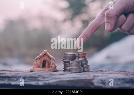 Mano selezionare monete impilare modello casa su tavola di legno Foto Stock